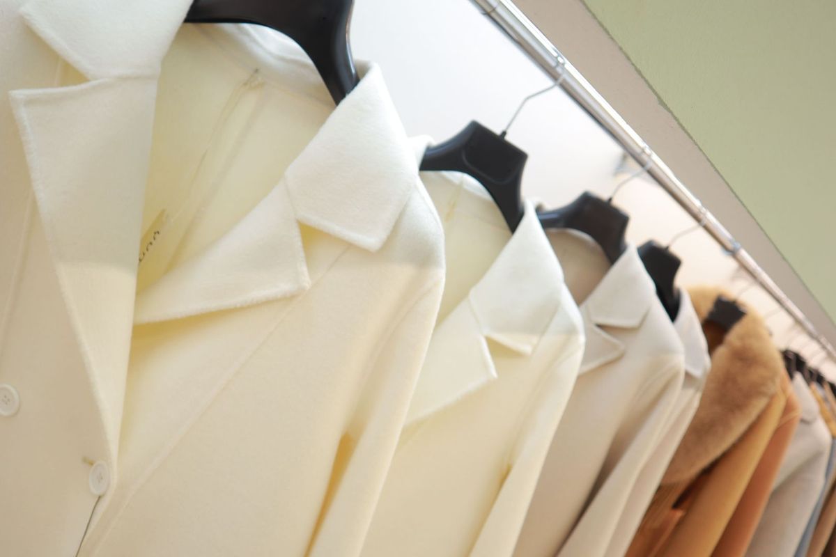 Dettaglio del revers di un cappotto avorio in lana, appeso nello showroom GIUPEL.