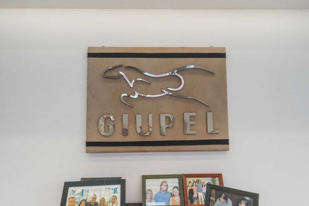 L’insegna storica GIUPEL, con il cavallo in corsa, e sotto le fotografie aziendali incorniciate.