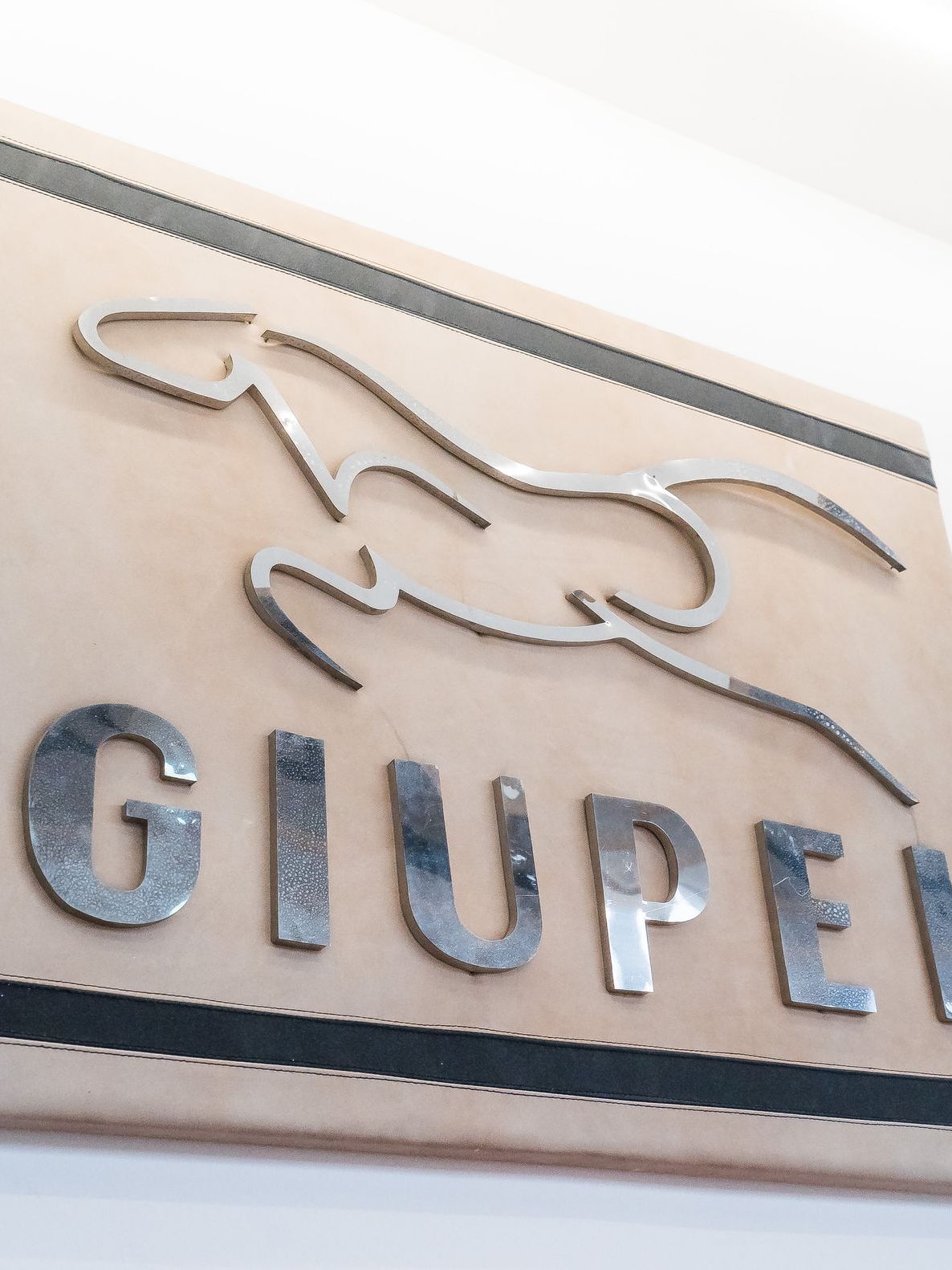 Insegna GIUPEL in metallo montata alla parete dello showroom.